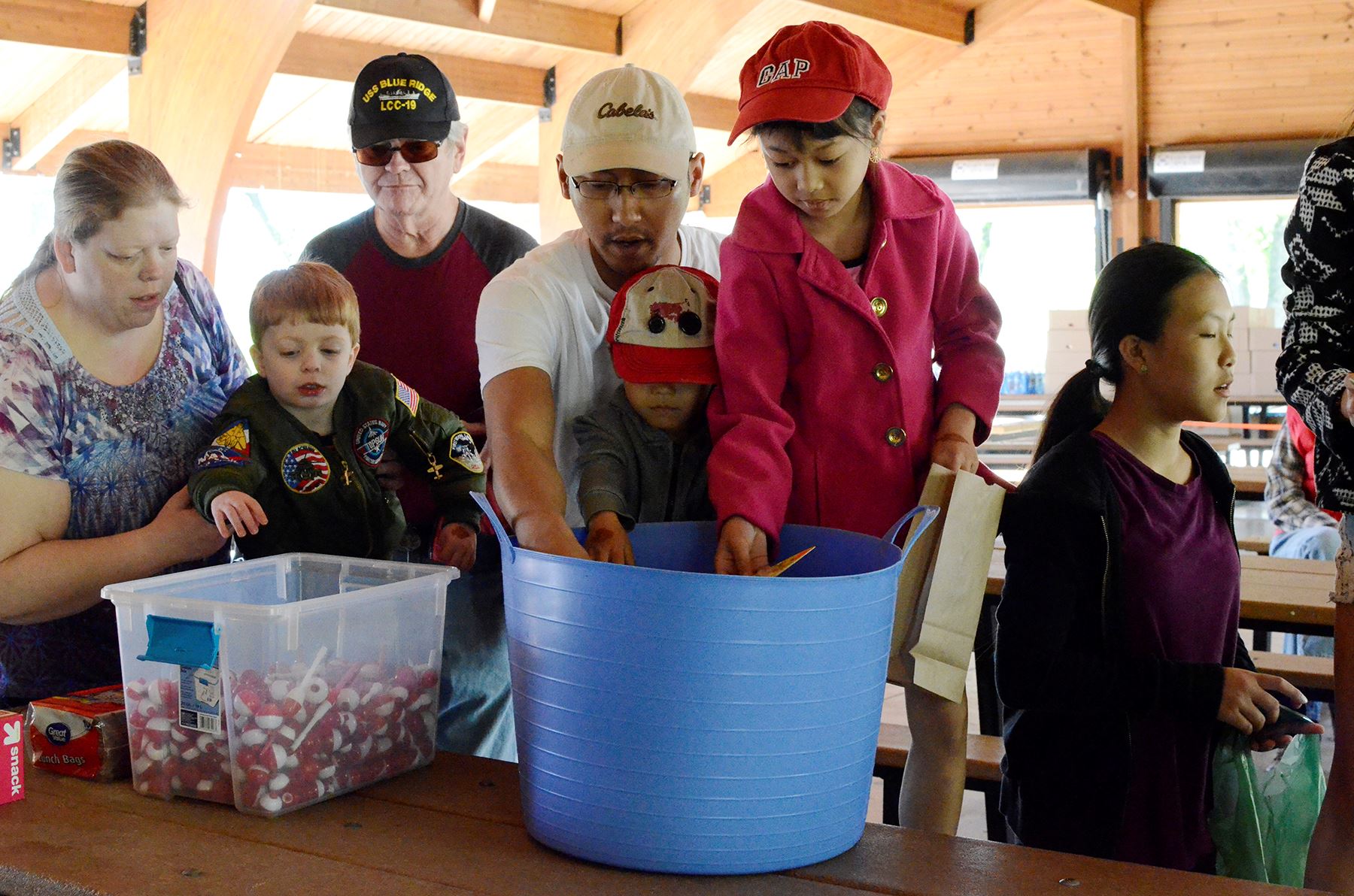 Children and adults reach in container for lures
