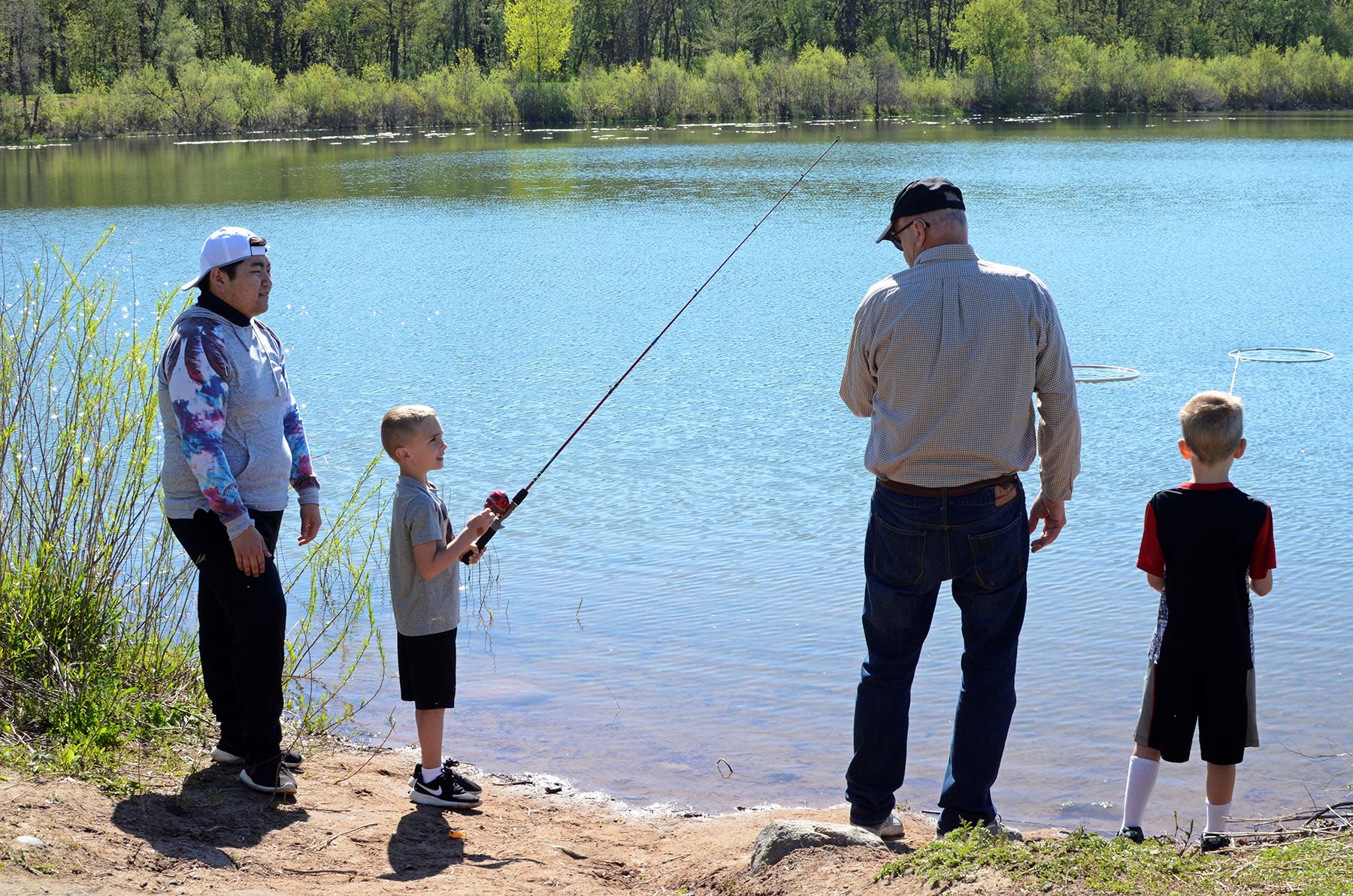 Children and adults fish by the shore