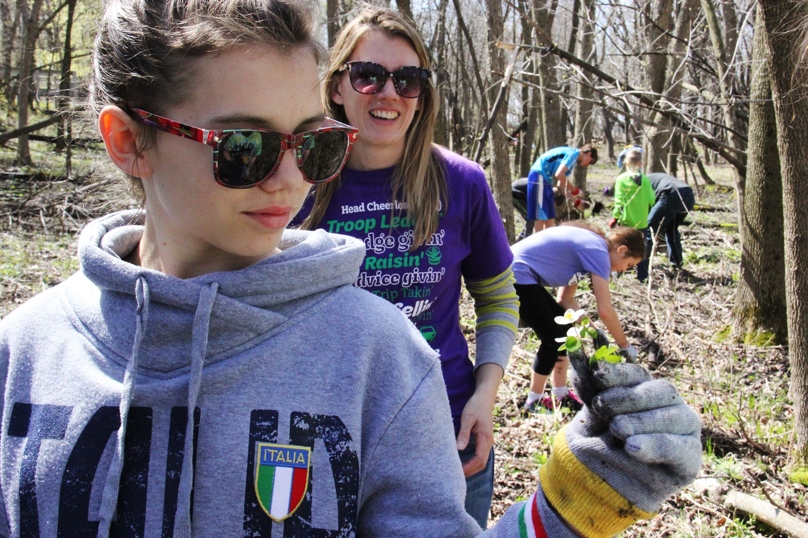 Young girl holds leaves with others working in the background